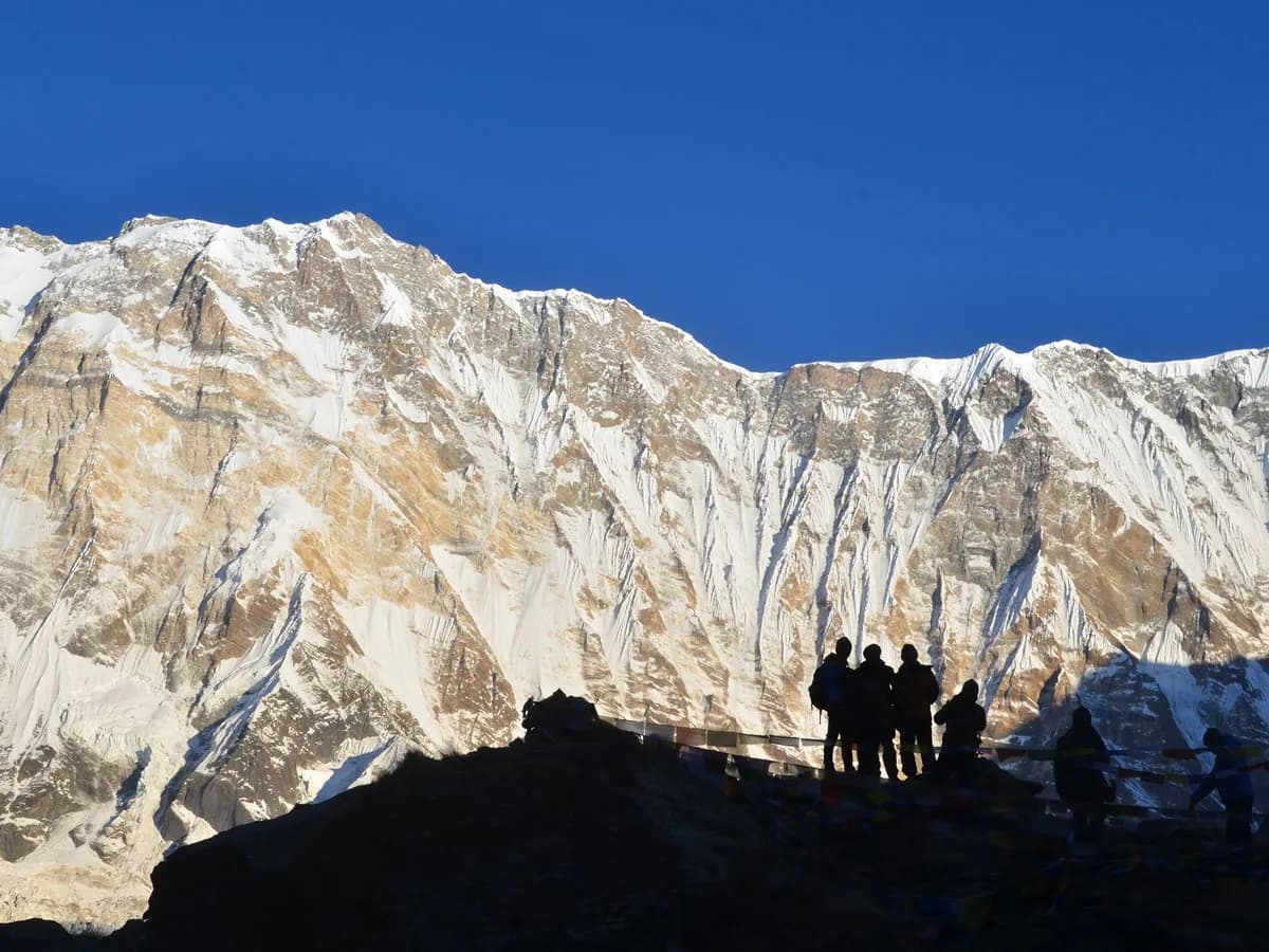 Trekkers standing at Annapurna Base Camp with giant snow covered Himalayan peak in background