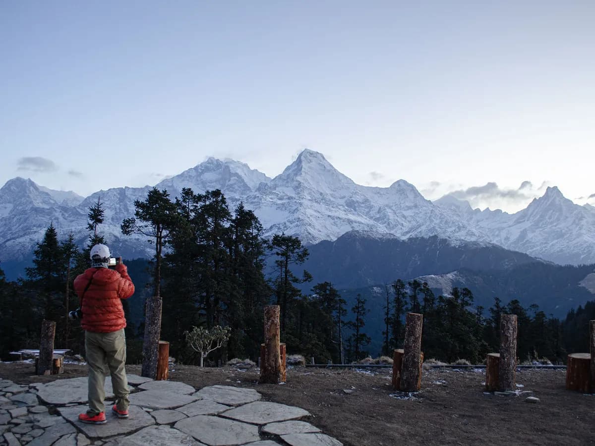 Trekker taking photos of the Annapurna mountain range at sunrise during the Annapurna Foothills Trek