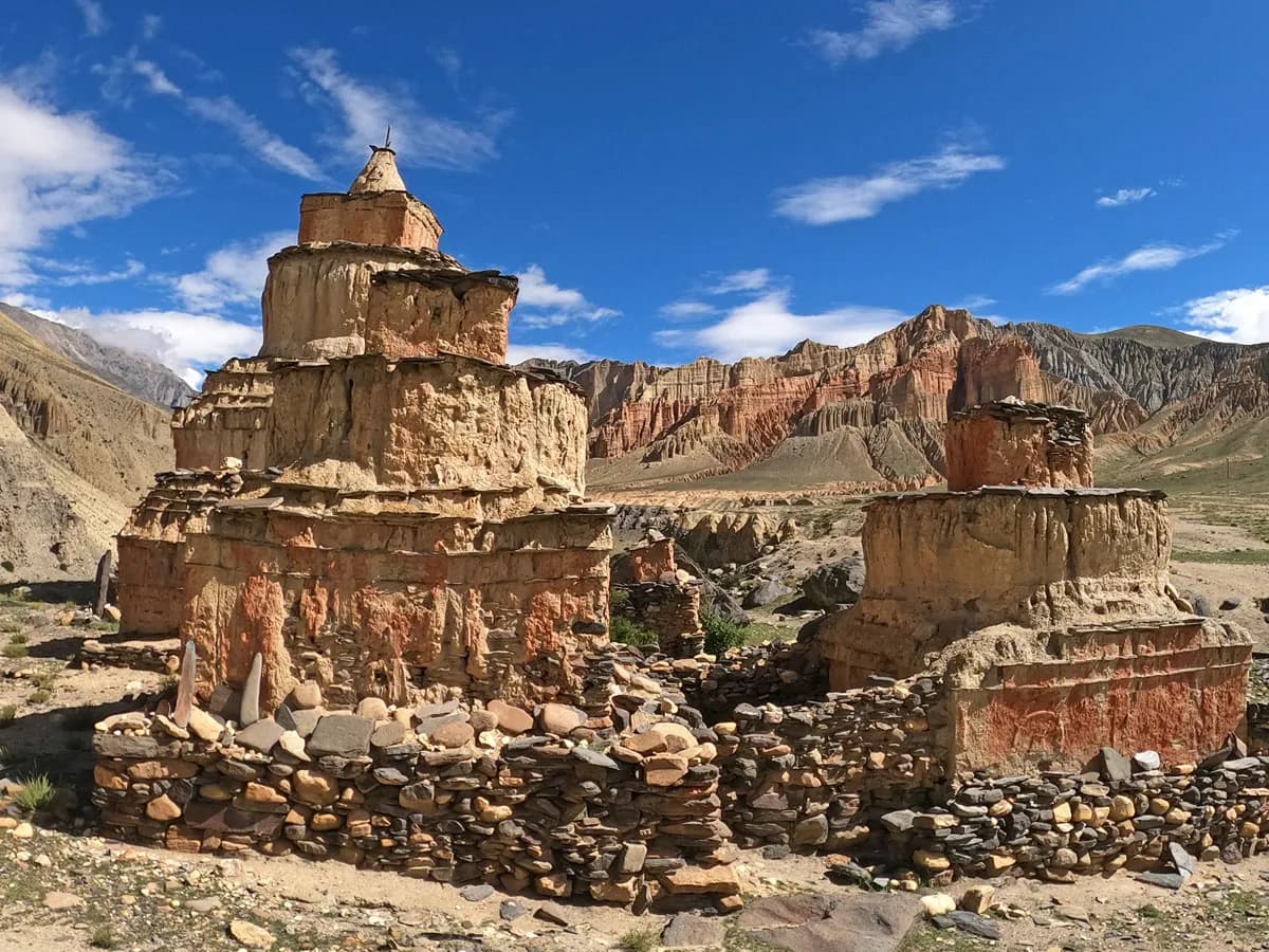 Ancient mud-brick chortens and stone walls set against the red cliffs of Dhakmar in Upper Mustang, Nepal.