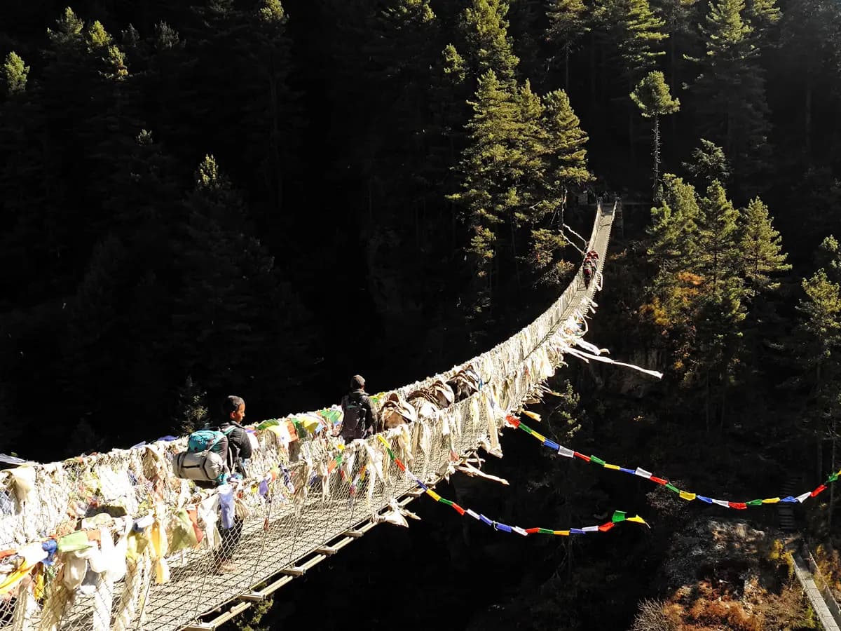 Suspension bridge draped in prayer flags over a river gorge on the Everest trek