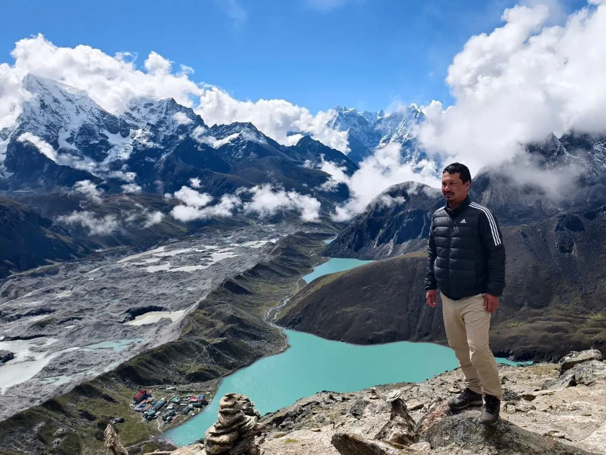 Hiker overlooking turquoise Gokyo Lakes and Ngozumpa Glacier from Gokyo Ri viewpoint.