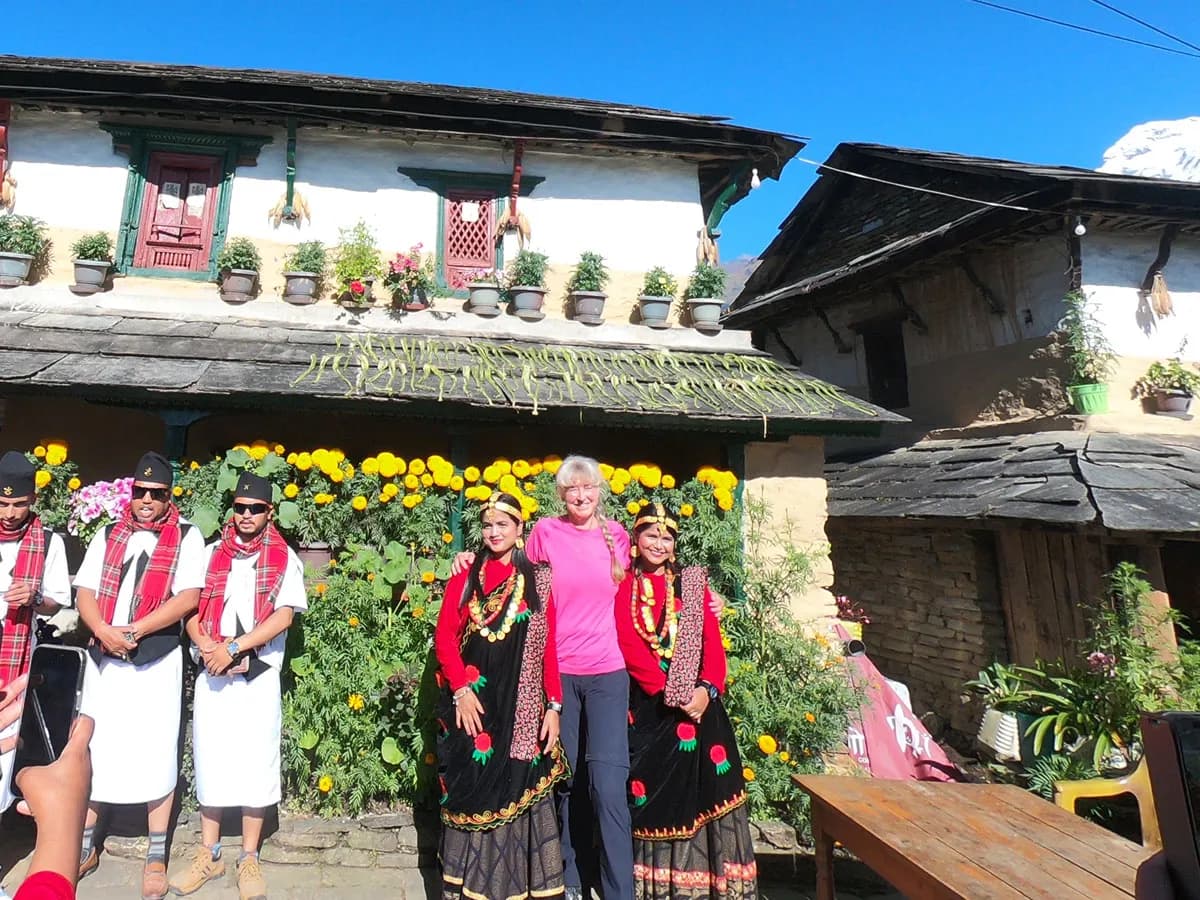 Tourist posing with locals in traditional Gurung ethnic dress in Ghandruk village.