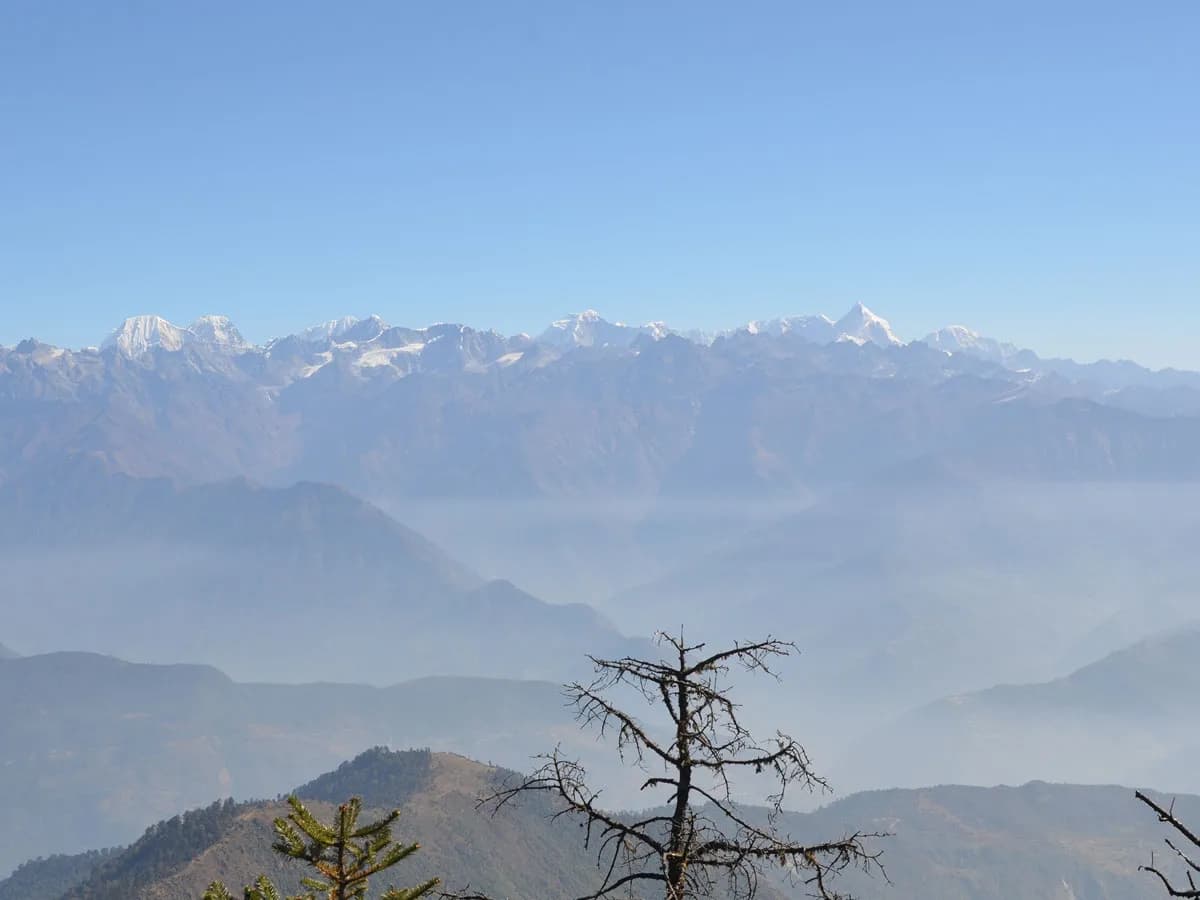 A clear blue-sky view of the high Himalayan mountain range with snow-draped summits like Gaurishankar stretching across the horizon