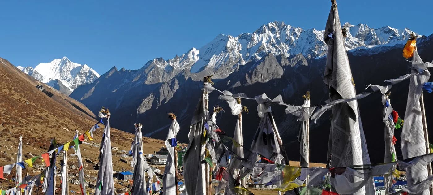 Buddhist prayer flags fluttering in the wind with high snow-capped peaks in Langtang Valley