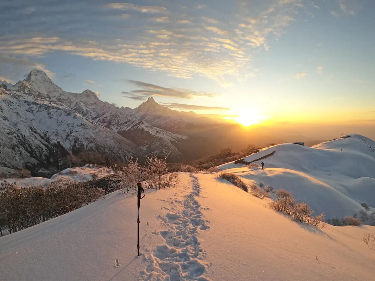 Golden sunrise casting light across a snow-covered trekking trail towards Annapurna and Machhapuchhre mountains on the Muldai Trek.
