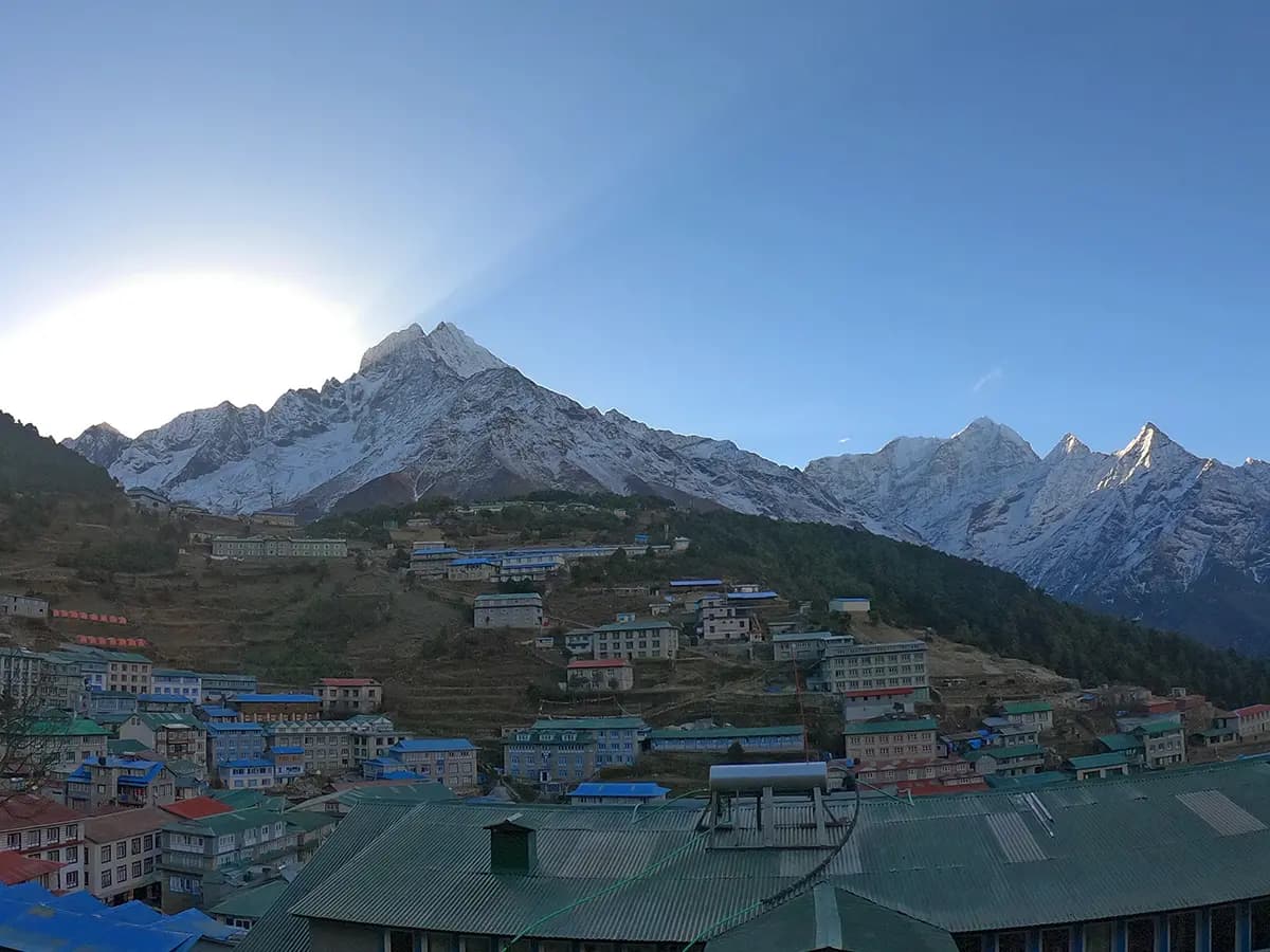 Morning view of colorful lodges in Namche Bazaar village surrounded by snow-capped Himalayan peaks.