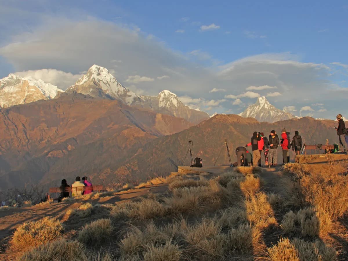 Trekkers standing on the Poon Hill viewpoint watching the sunset illuminated over the Annapurna mountain range in Nepal.