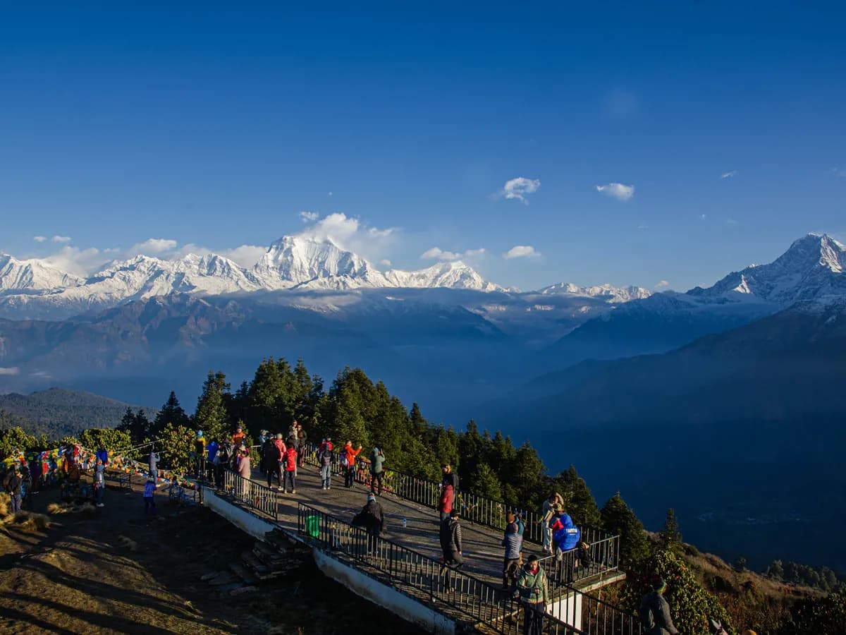 Panoramic view of travelers gathering at the Poon Hill viewpoint overlooking snow-covered Himalayan peaks