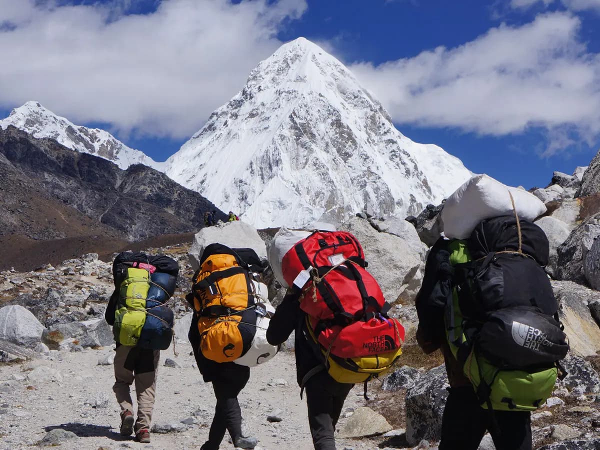 Porters carrying duffel bags on the Everest Base Camp trail.