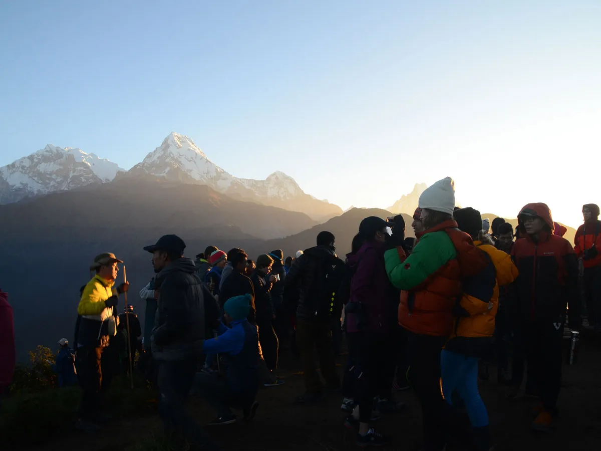 Group of trekkers gathered at Poon Hill viewpoint watching the morning sunrise over the Himalayas