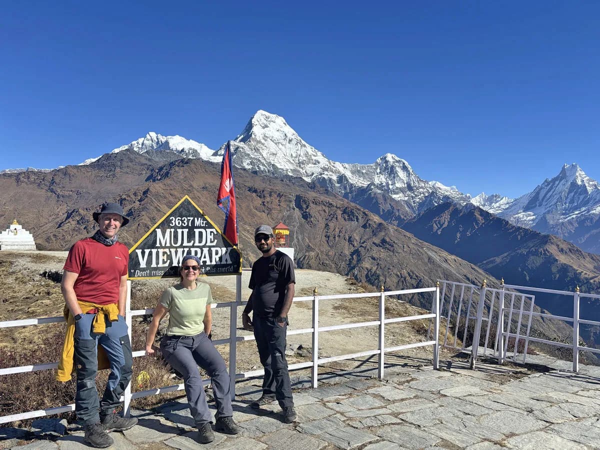 Trekkers standing by the Muldai View Park signpost at 3,637 meters with the Annapurna range behind them
