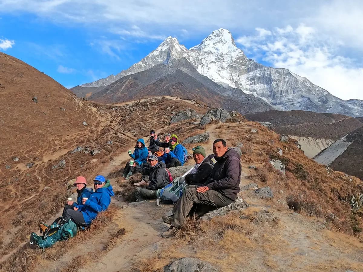 Trekkers resting on a mountain ridge with Mount Ama Dablam in the background