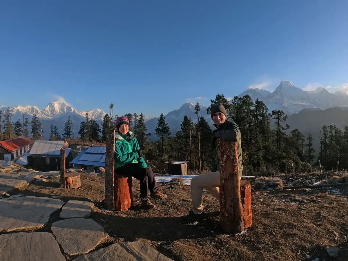 Two trekkers sitting outdoors with mountain backdrop