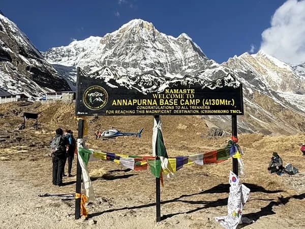 Welcome sign board at ABC with snow-capped mountain peaks