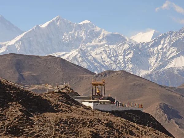 Scenic view of Muktinath shrine and colorful prayer flags with snow-capped Himalayan mountains in the background during the Jomsom Muktinath Trek
