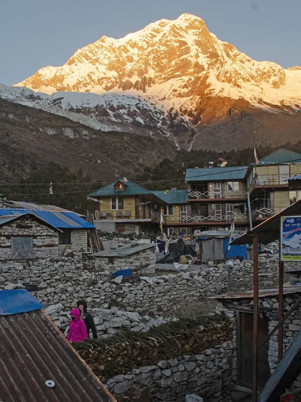 Golden sunrise over the mountain soaring above stone houses and lodges in Samagaon village along the Manaslu Circuit Trek in Nepal