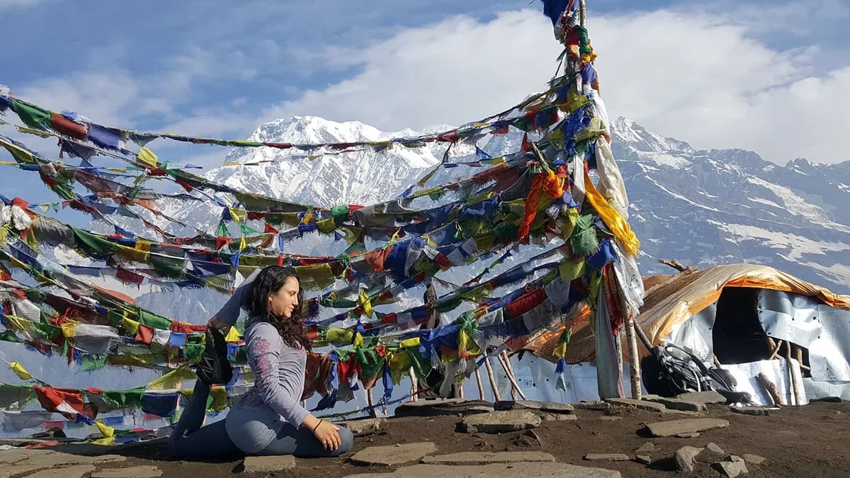 trekker at mardi himal viewpoint with yoga pose and prayer flags with mountain view