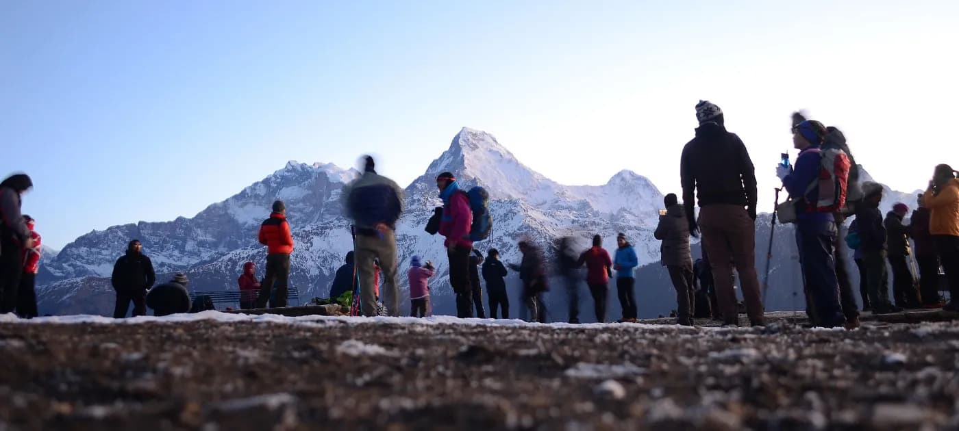 Silhouettes of numerous trekkers gathered on the ridge at Poon Hill watching the early morning sunlight hit the Annapurna mountains