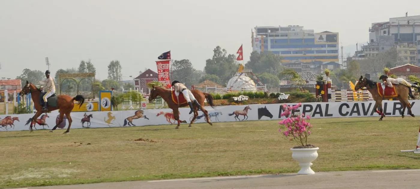 Nepal Cavalry horse riders performing equestrian stunts on moving horses in front of the Nepal Cavalry banner at Tundikhel.