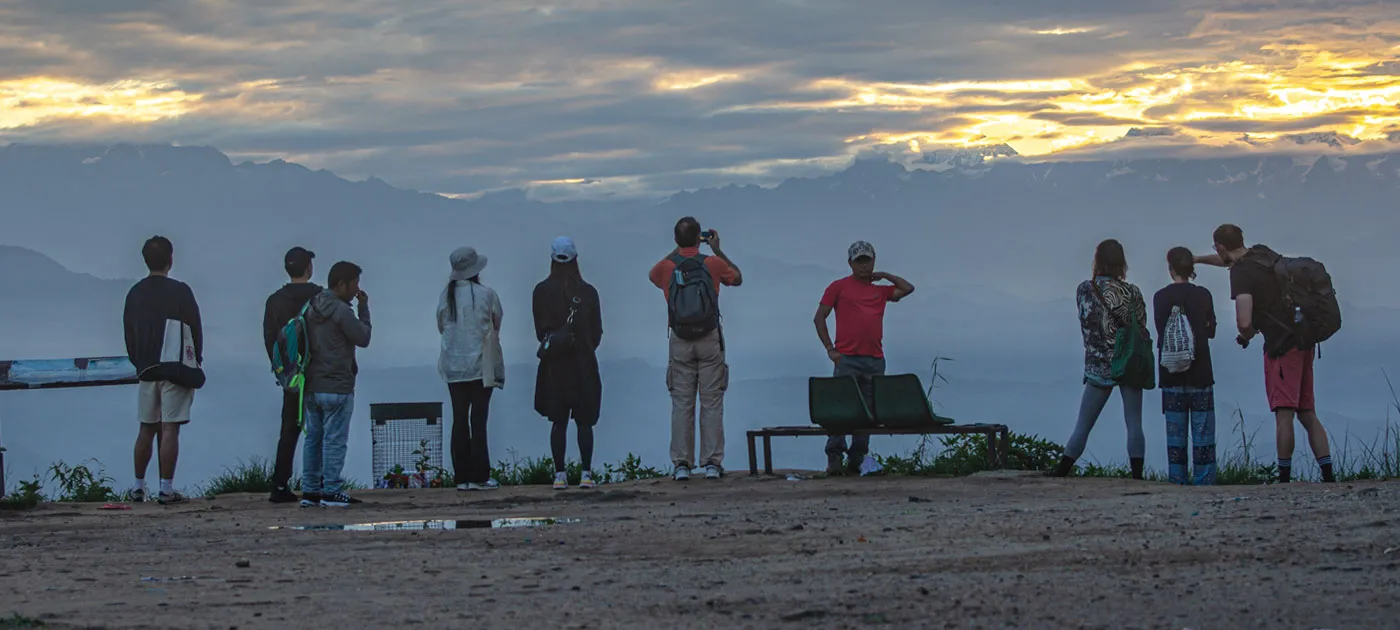 Silhouetted tourists gathered on a hill viewing the Himalayan mountain range at sunrise during a Nagarkot day hike