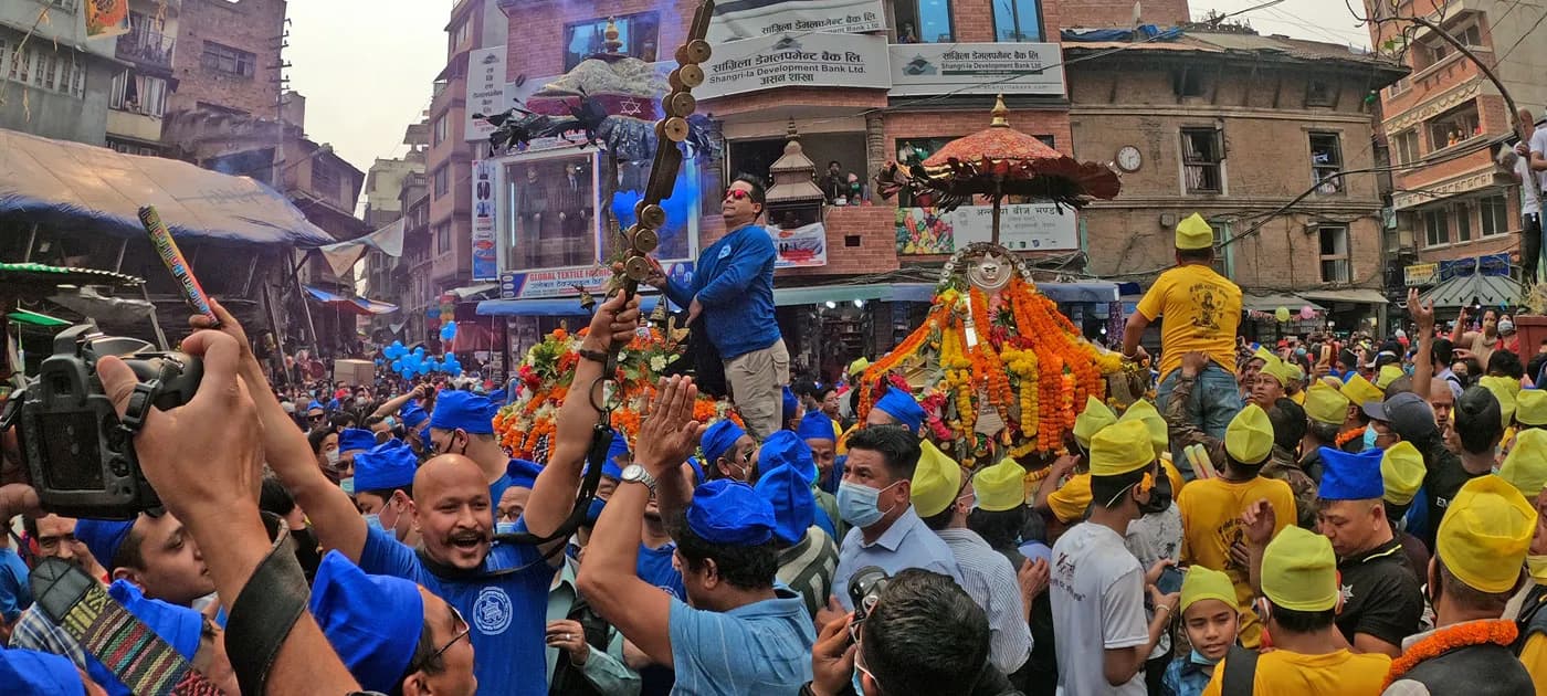 A high-angle photo of two portable goddess palanquins surrounded by crowds of participants in blue and yellow caps during the Dyah Lwakegu ceremony.