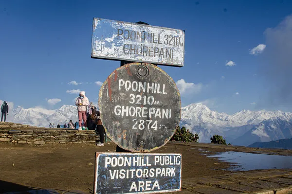 Informational signboards at Poon Hill showing elevations of 3,210 meters for Poon Hill and 2,874 meters for Ghorepani with the Annapurna mountain range in the background