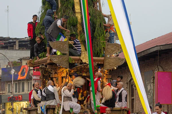 Traditional priests and caretakers performing sacred rituals atop the decorated wooden platform of the Seto Machindranath chariot during the festival procession in Kathmandu
