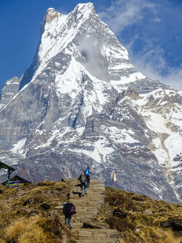 Trekkers walking up stone stairs toward Mount Machapuchare Fishtail Peak in the Annapurna region near Pokhara.