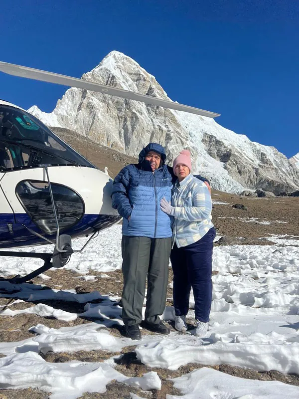 Travelers posing next to a helicopter with snowy Mount Everest region peaks in the background during a high-altitude helicopter tour in Nepal.