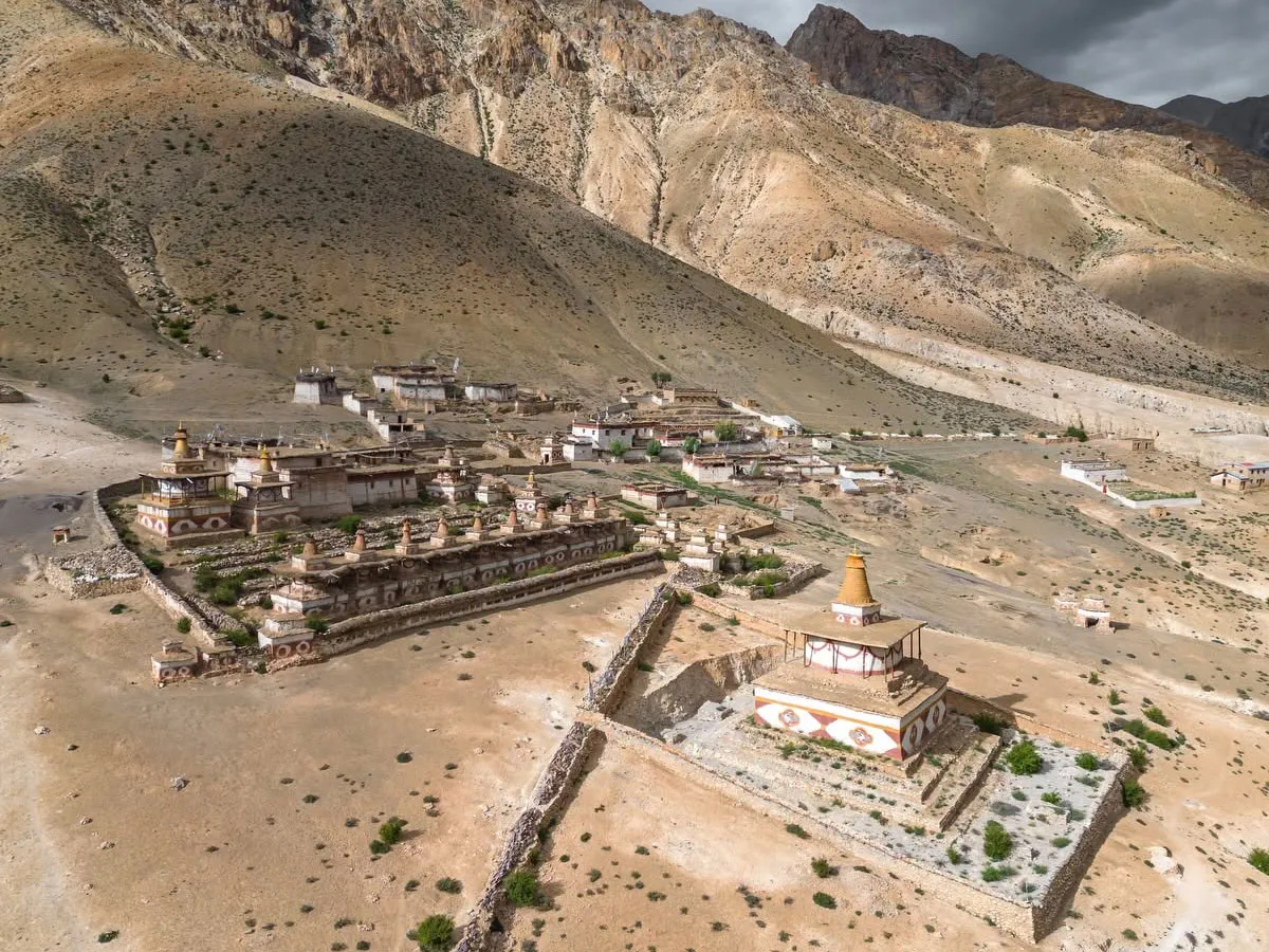 Aerial view of a historic cluster of Buddhist stupas and mud-brick buildings in the arid Dolpo valley.
