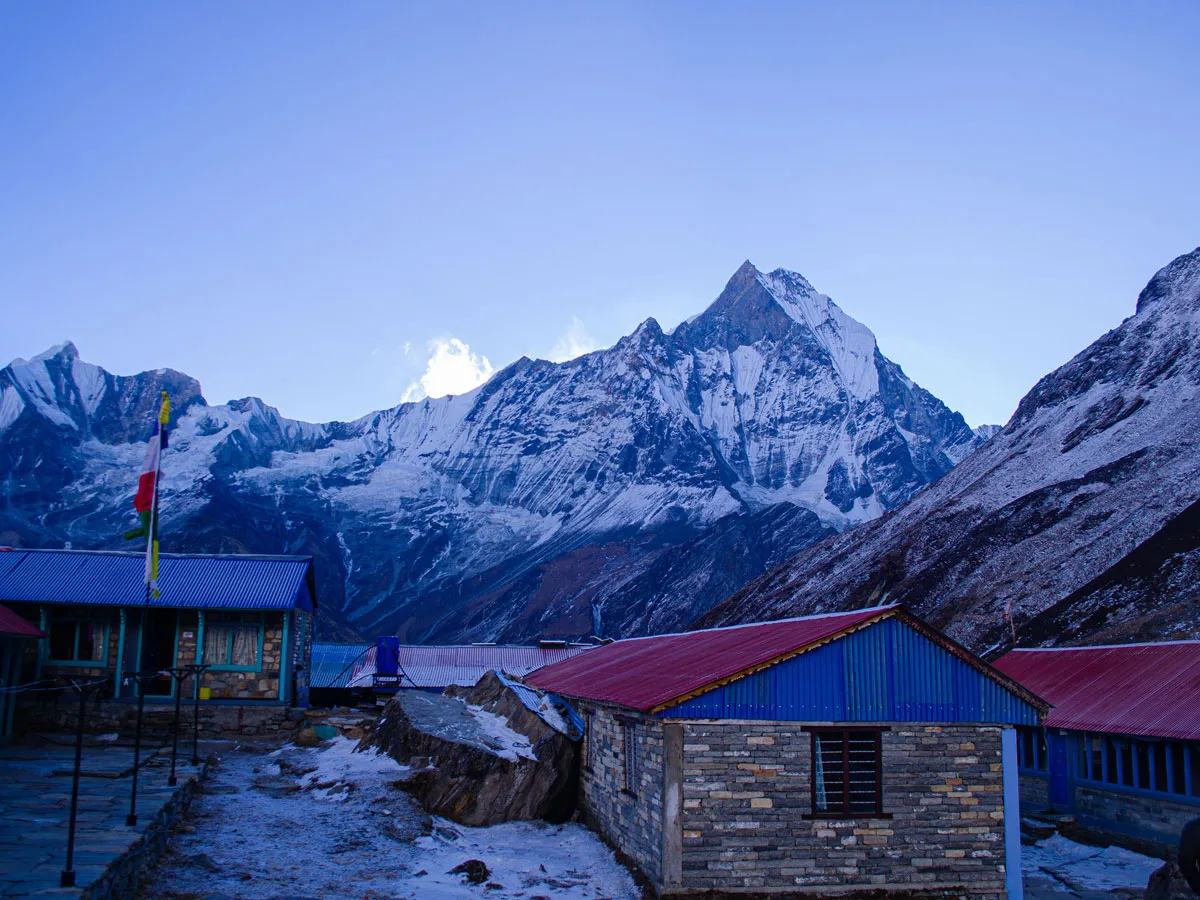 Stone teahouses sitting beneath the towering peak of Mount Machhapuchhre in ABC