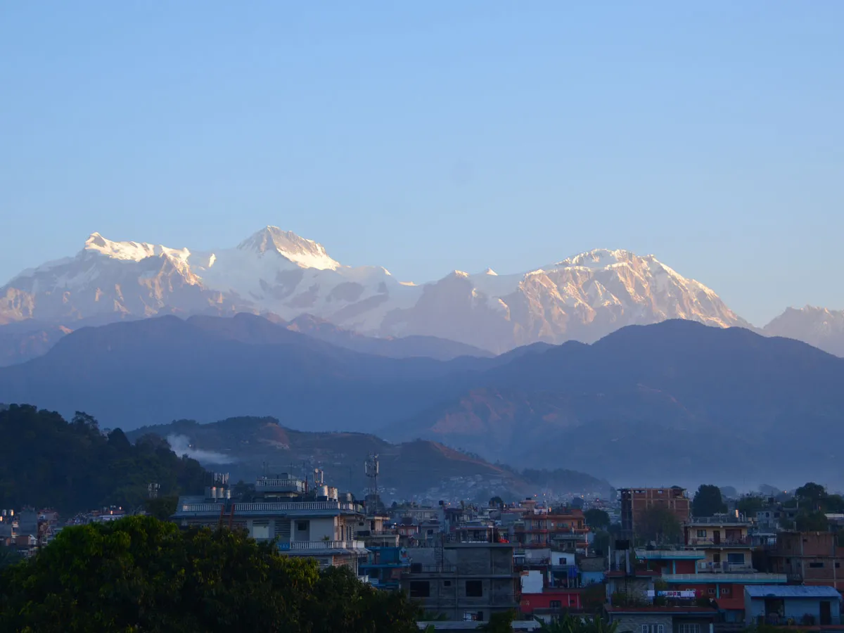 Panoramic view of the snow-capped Annapurna mountain peaks towering over Pokhara valley at morning light.