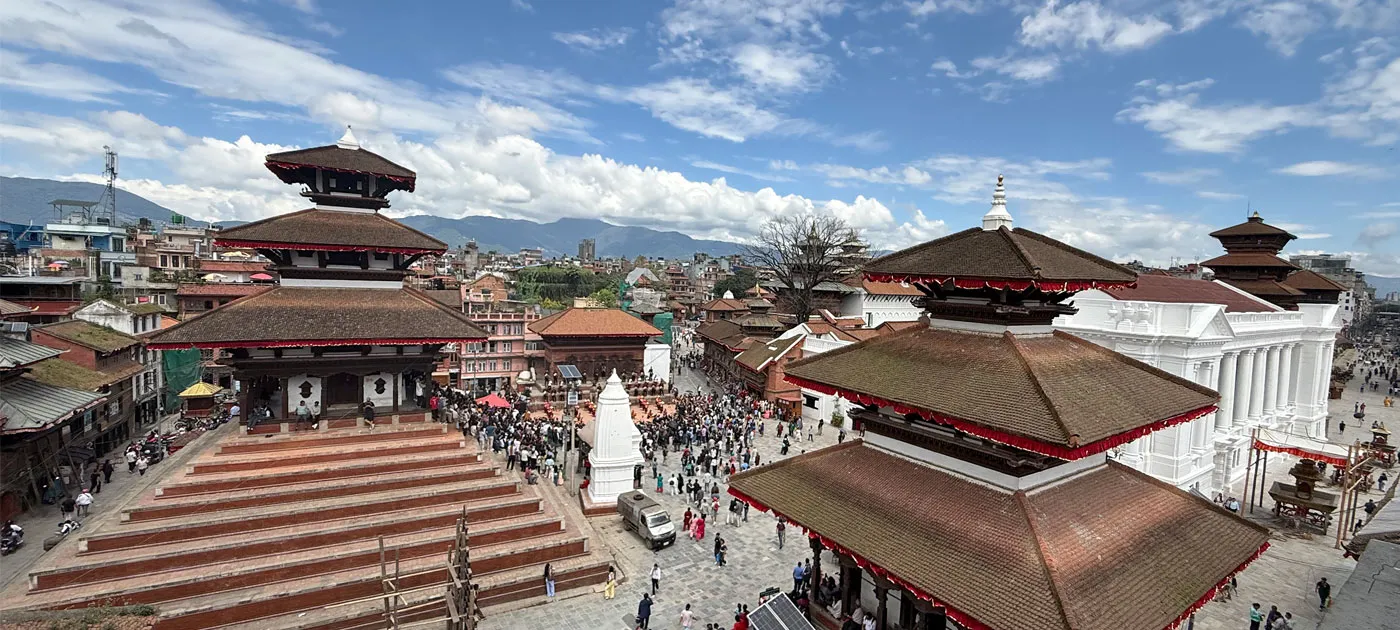A high-angle panoramic view of traditional multi-tiered pagoda temples and bustling crowds in Kathmandu Durbar Square