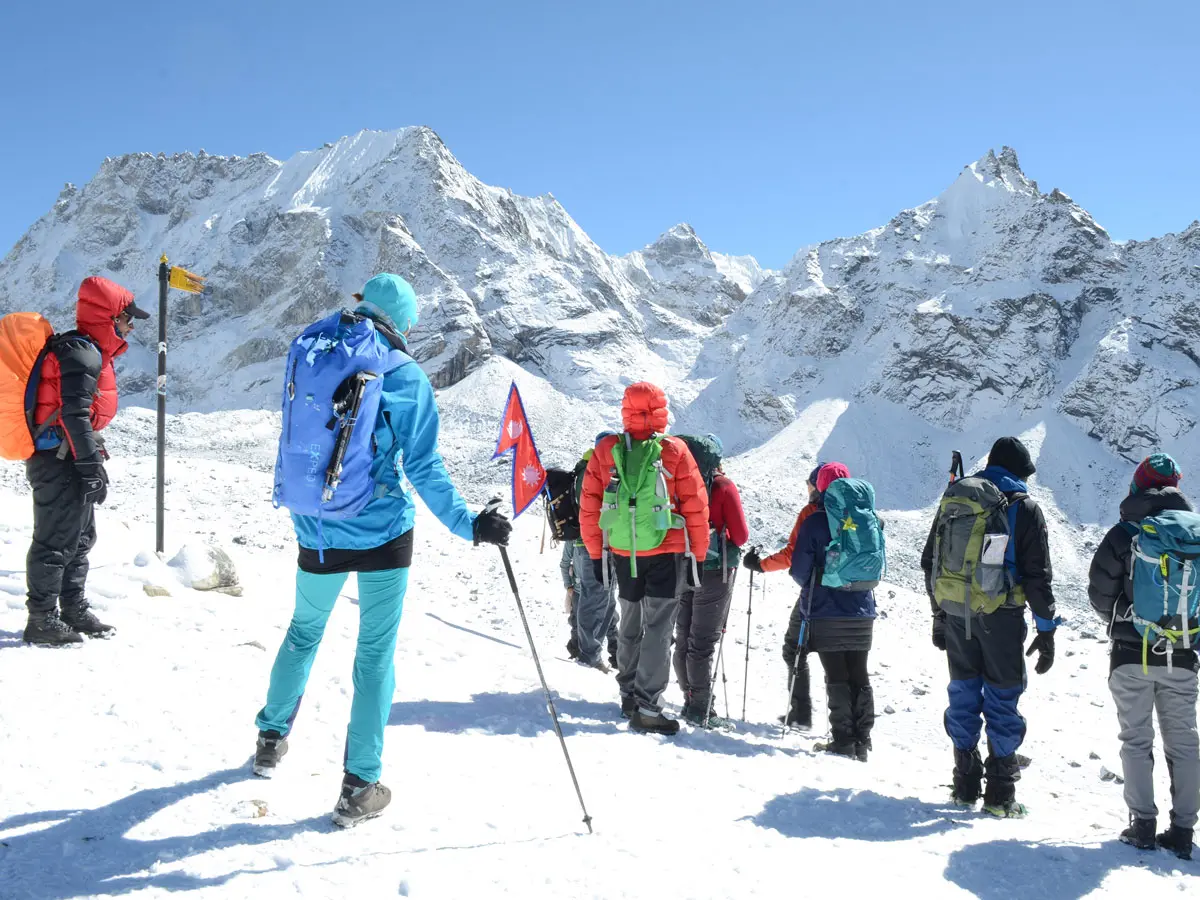 Group of trekkers walking on a snowy mountain trail with backpack gear near Cho La Pass.
