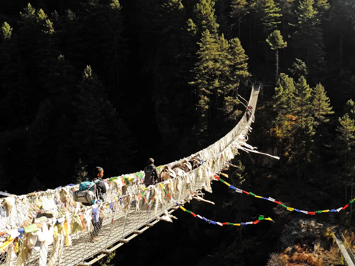 Suspension bridge draped in prayer flags over a river gorge on the Everest trek