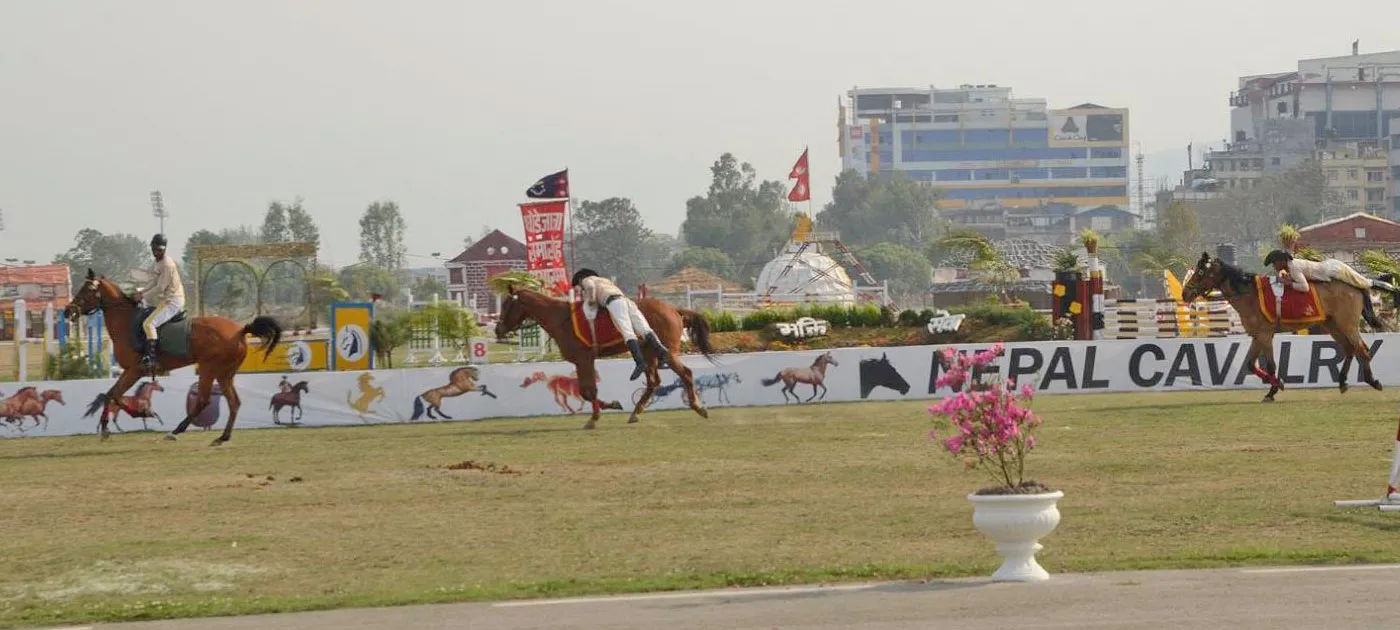 Nepal Cavalry horse riders performing equestrian stunts on moving horses in front of the Nepal Cavalry banner at Tundikhel.