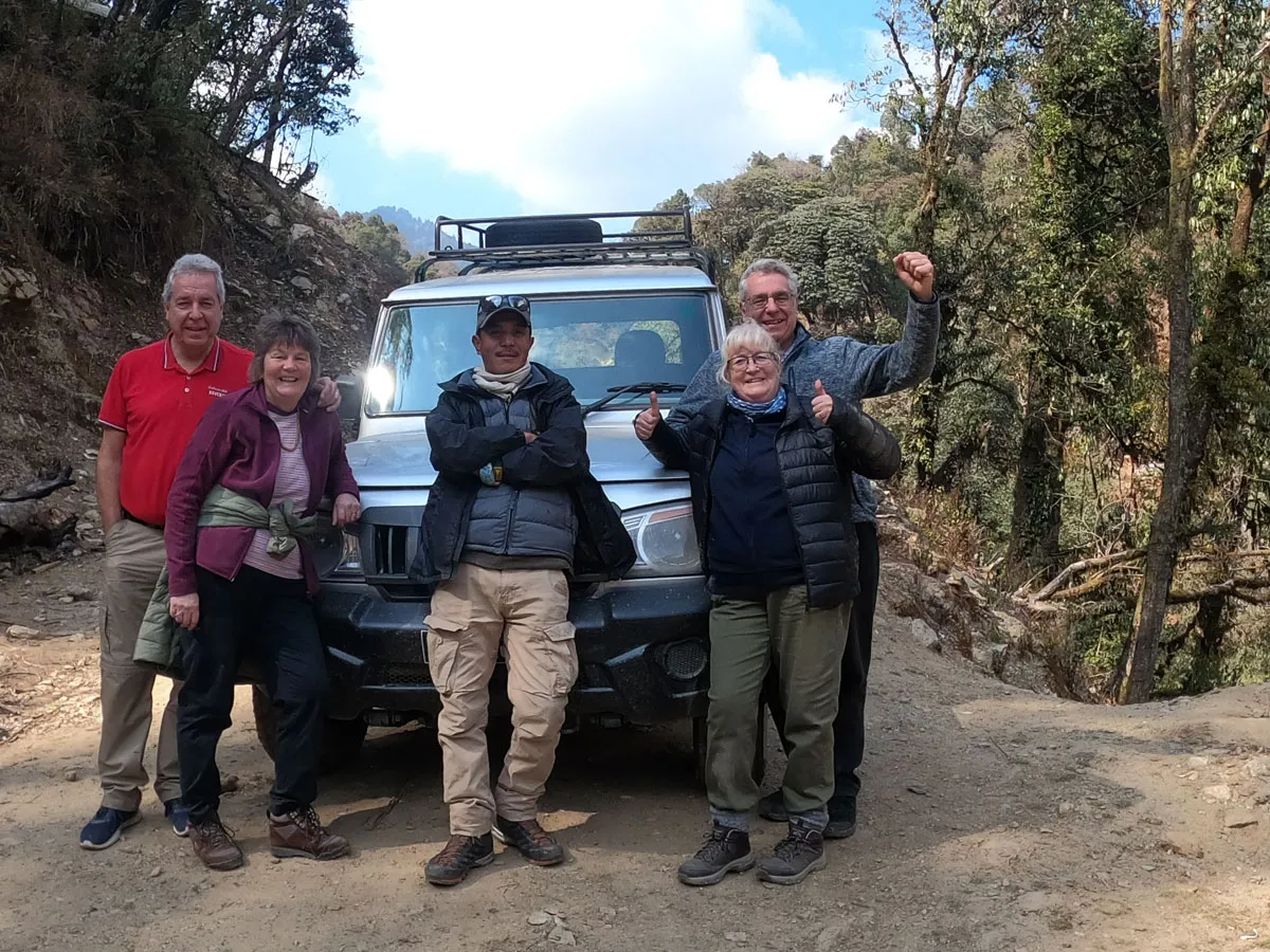 Trekkers posing in front of a 4WD Jeep on a mountain road during the 2-Day Ghorepani Poon Hill Drive and Trek in Nepal