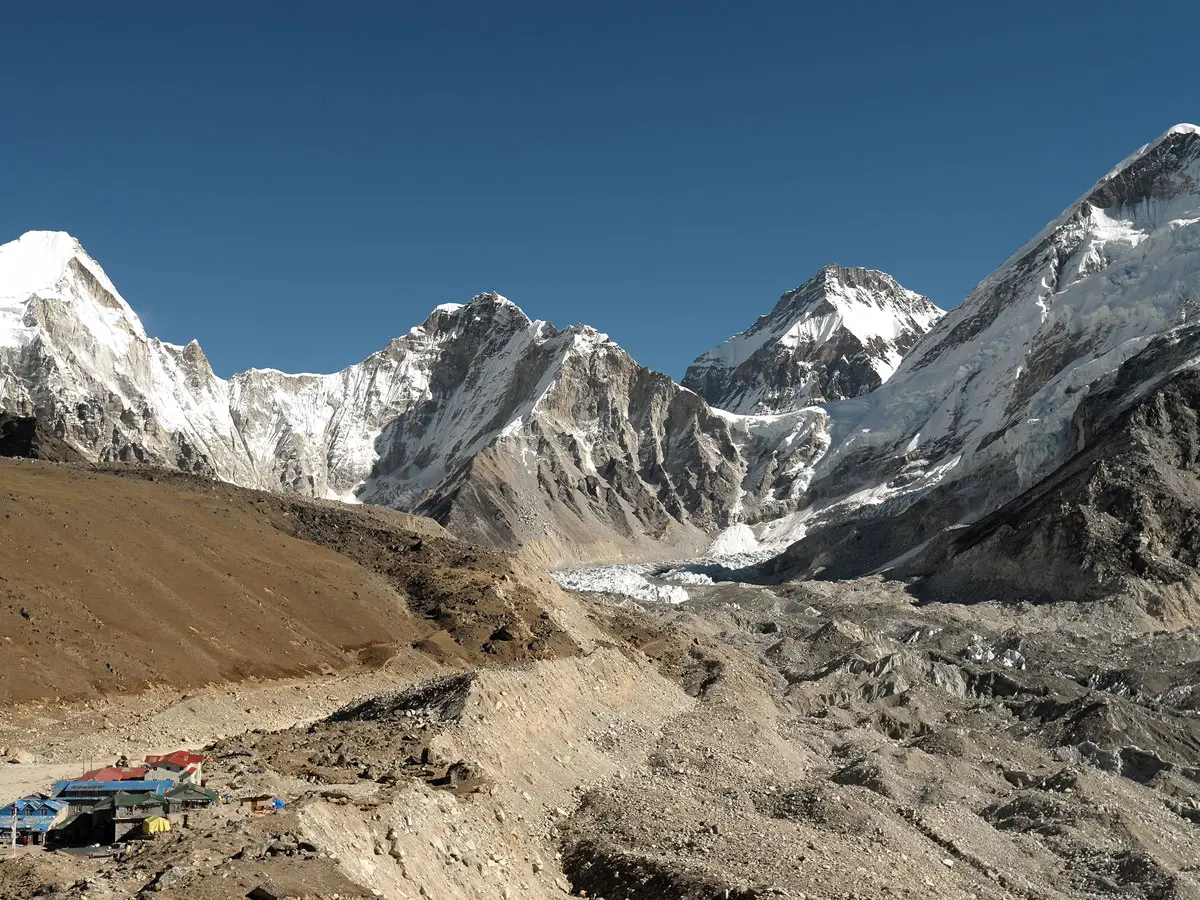 Panoramic view of Gorakshep teahouses and the rocky Khumbu Glacier framed by snow-capped Himalayan peaks.