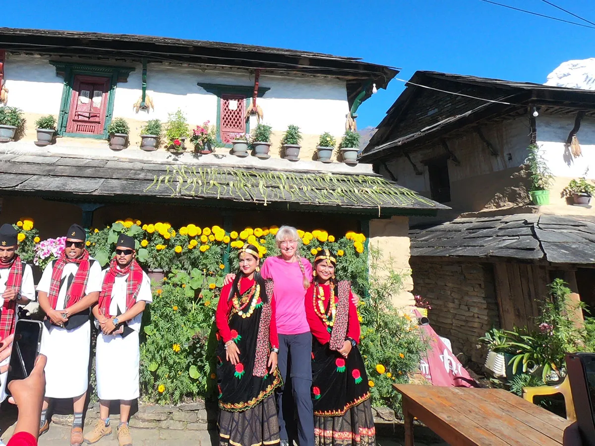 Tourist posing with locals in traditional Gurung ethnic dress in Ghandruk village.