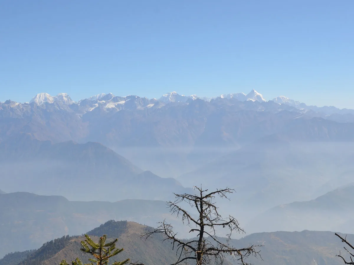 A clear blue-sky view of the high Himalayan mountain range with snow-draped summits like Gaurishankar stretching across the horizon