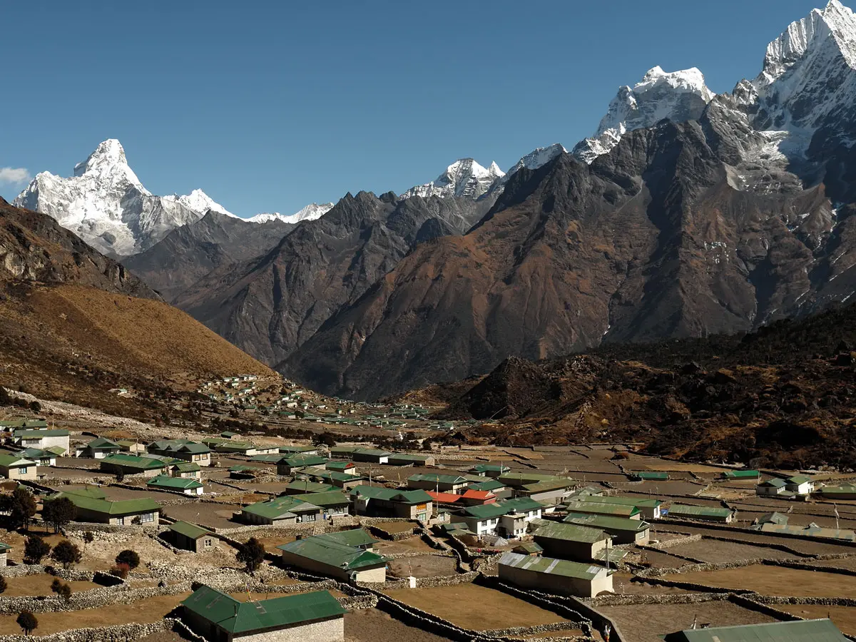 Scenic mountain village in a valley surrounded by towering snow-capped peaks.