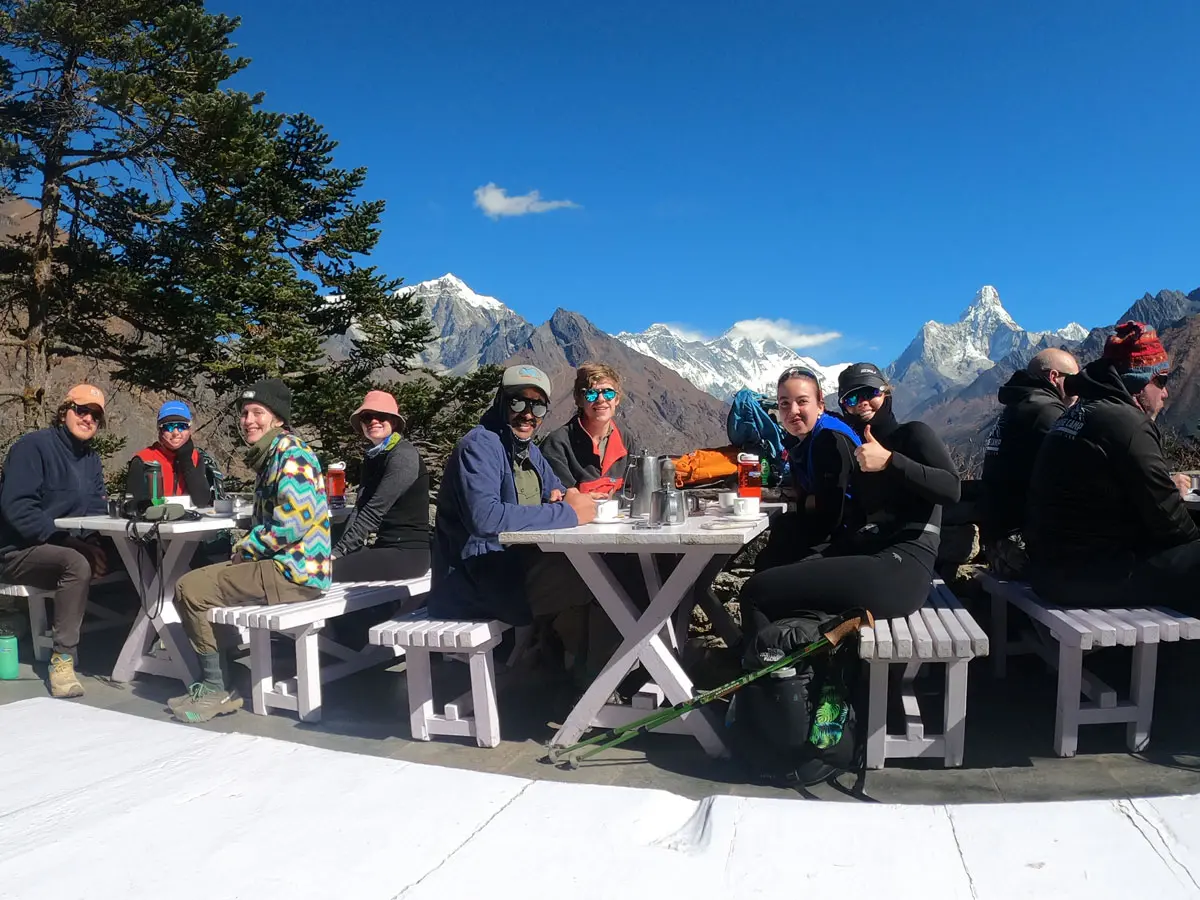 Group dining outdoors with Himalayan mountain views