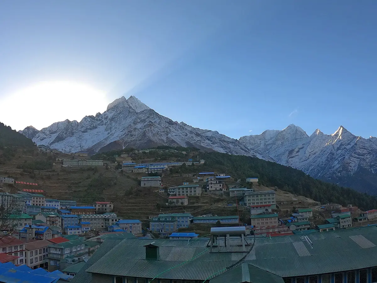 Morning view of colorful lodges in Namche Bazaar village surrounded by snow-capped Himalayan peaks.