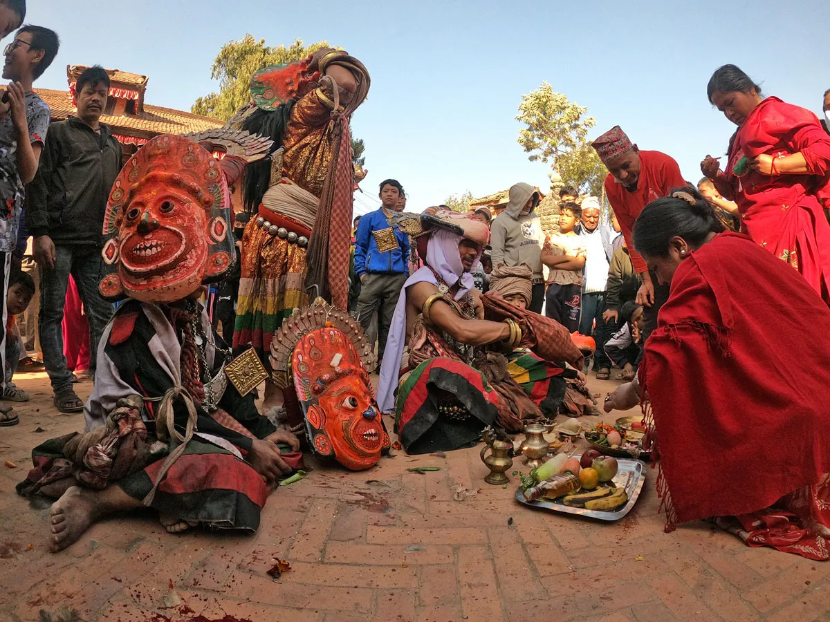 Performers wearing traditional red wooden masks and ritual costumes during a cultural festival ceremony in Nepal.