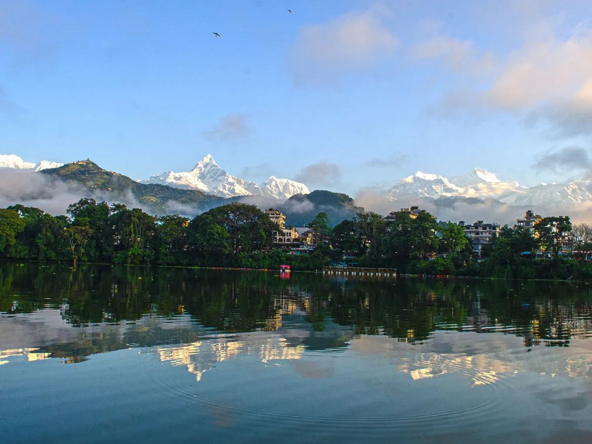 A wide scenic view of Phewa Lake in Pokhara with gentle water ripples reflecting the Machhapuchhre peak and Annapurna Himalayan range