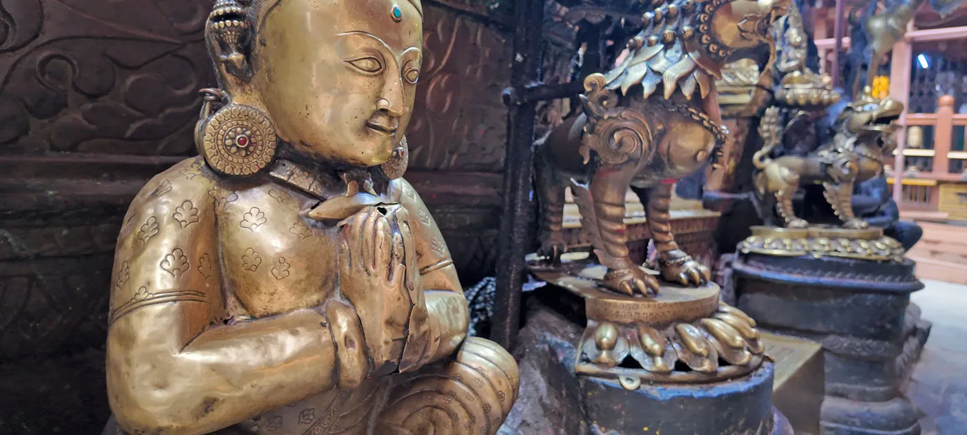 Brass statue performing the traditional folded-hands Namaste gesture at a Nepali temple.