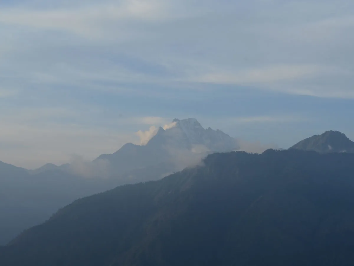 Distant snow-capped Himalayan peak rising above misty mountain ranges along the Guerrilla Trek Trail