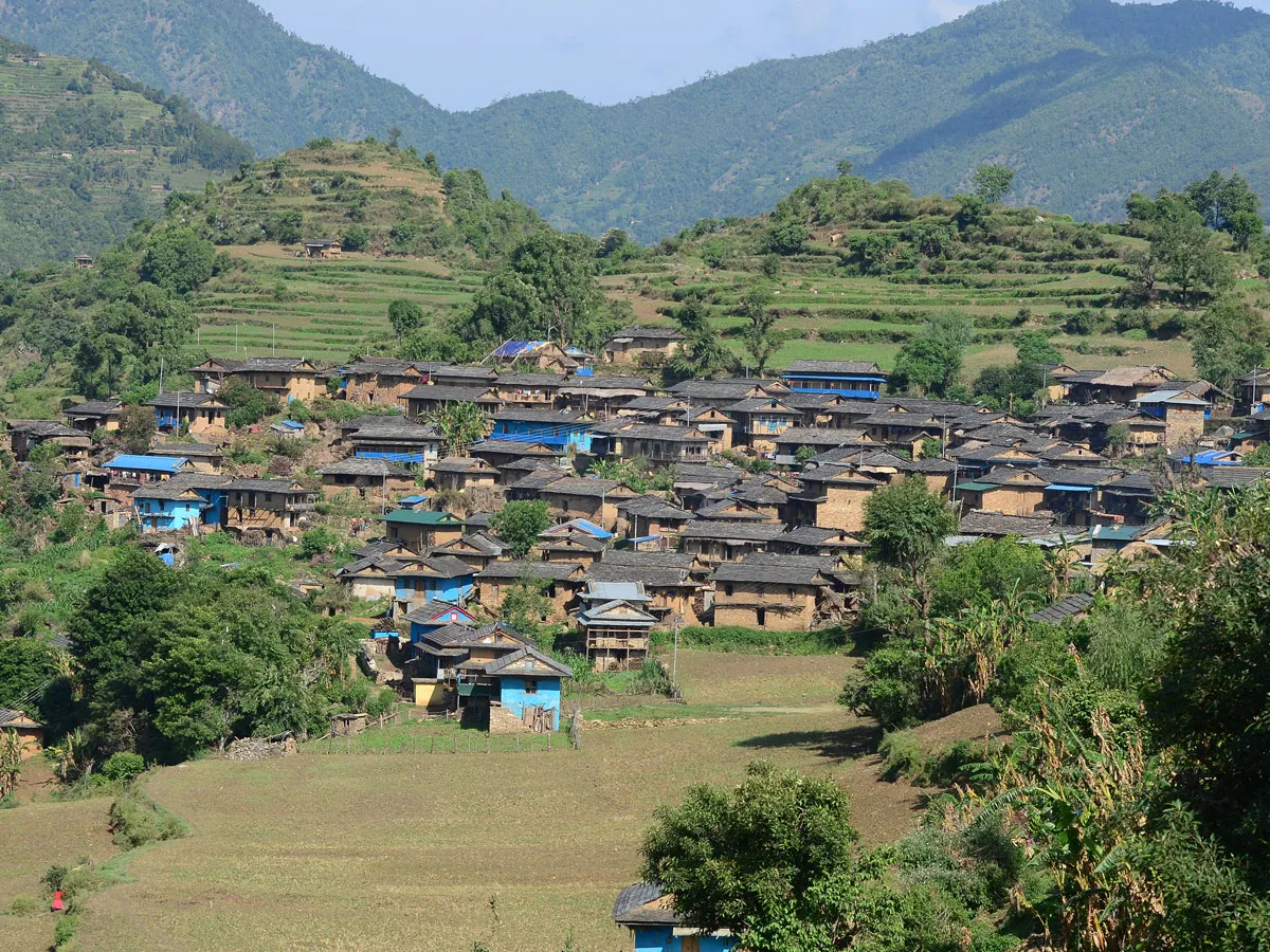 Scenic view of a traditional stone-roof village nestled among terraced fields on the Guerrilla Trek in Nepal