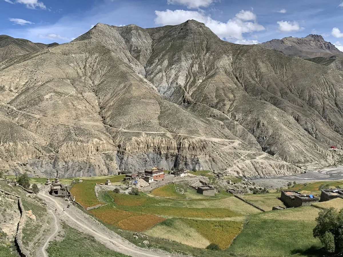 Traditional Tibetan-style monastery and village nestled in a valley beneath massive dry mountains in Dolpo.