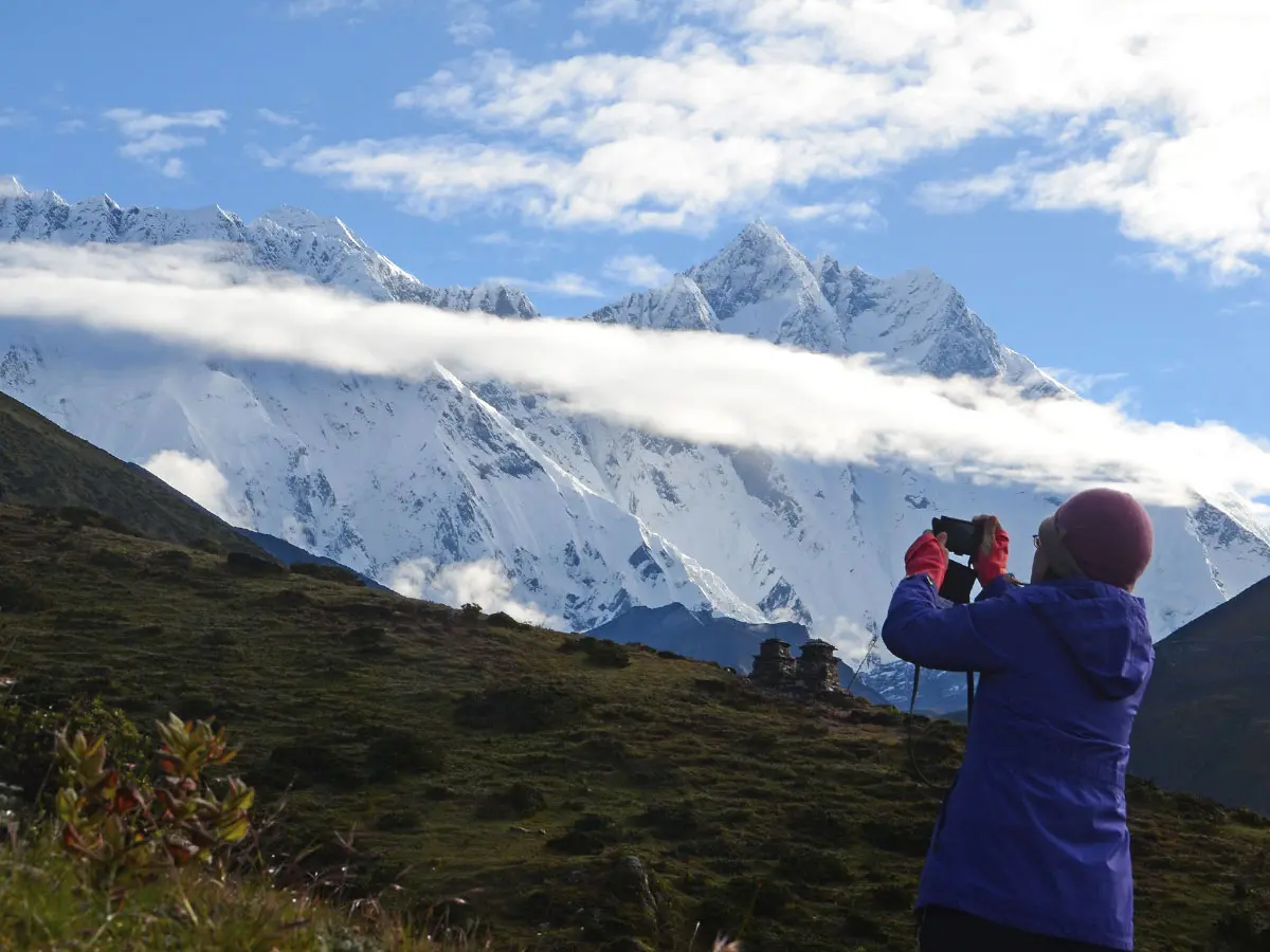 A trekker taking a photo of snow-covered mountain peaks in the Everest region